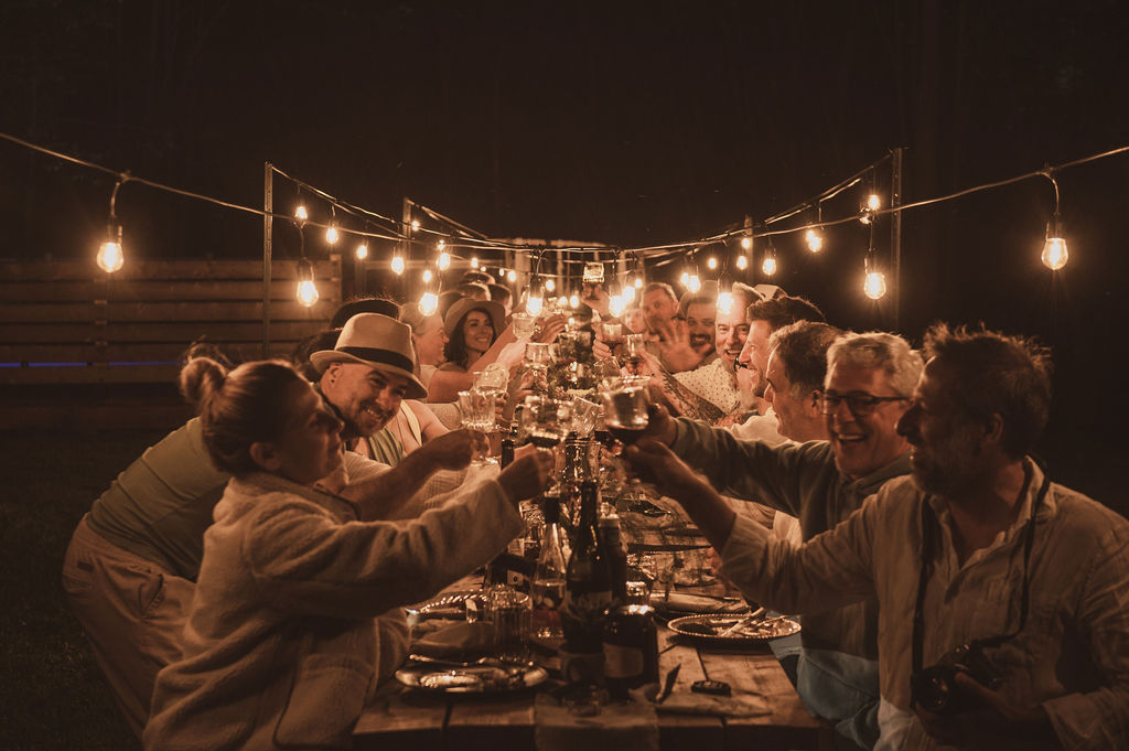 Group of people celebrating around an outdoor table in the evening
